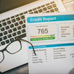A credit report with a score of 765 and a laptop in the background.